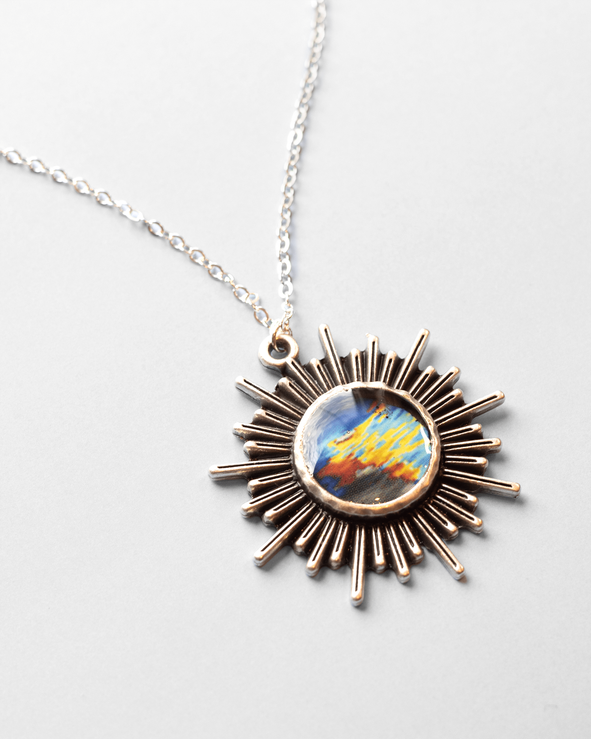 Handmade ultrasound heart necklace featuring real heart imagery. Vibrant sun shaped anatomical science jewelry gift for women in STEM and medicine. Side shot.