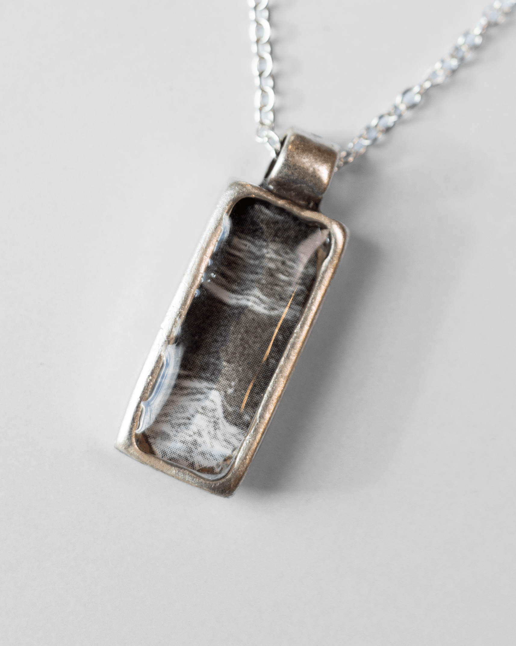 Ultrasound heartbeat necklace handmade in resin. Science jewelry art pendant symbolizing rhythm, sound, and human connection. Macro shot.
